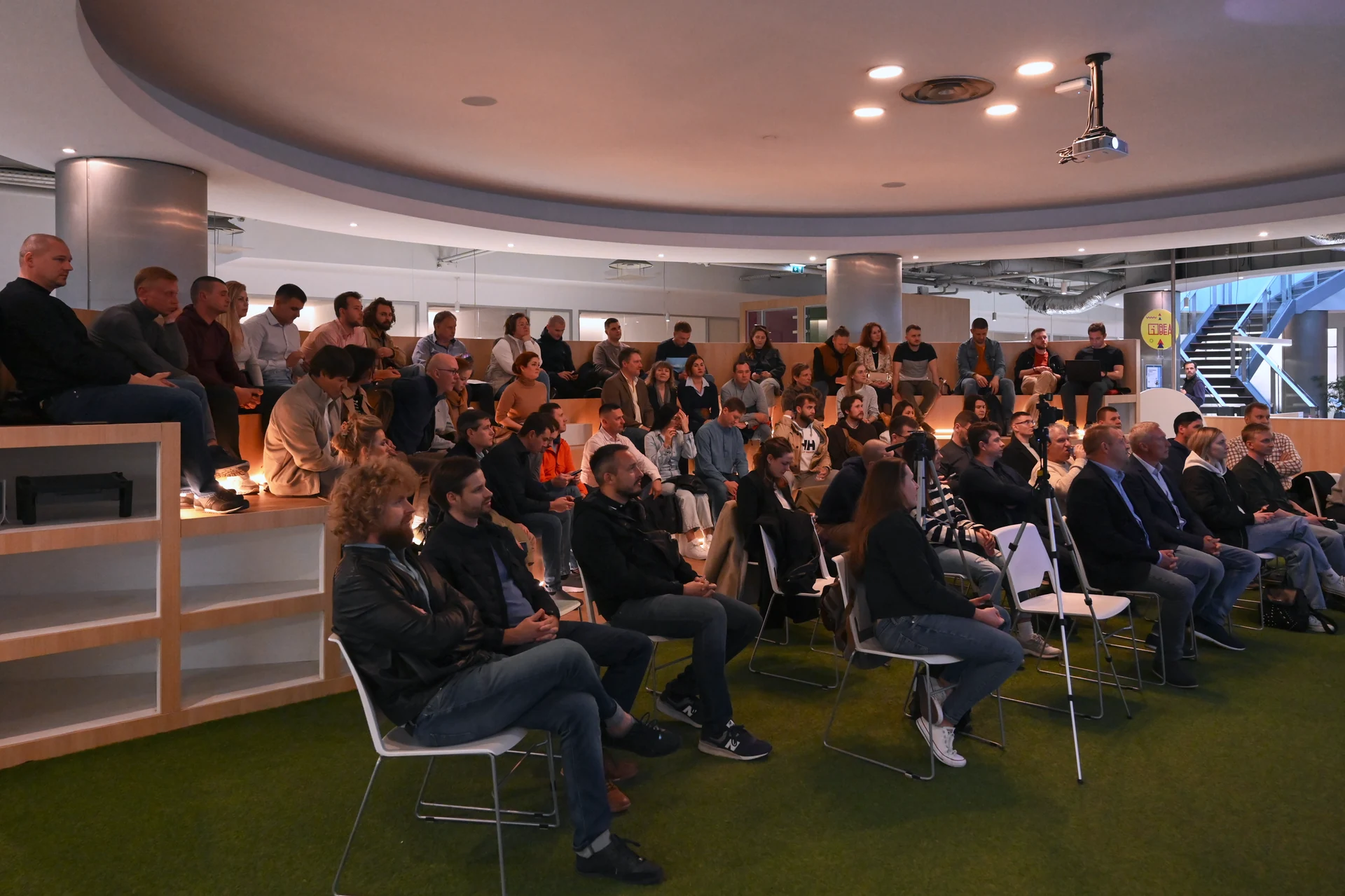 Участники Real Estate Meetup сидят в зале IDEA Spaces перед экраном презентации