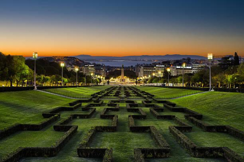 Wide angle view of Eduardo VII Park in LIsbon at sunrise with the city in the background.